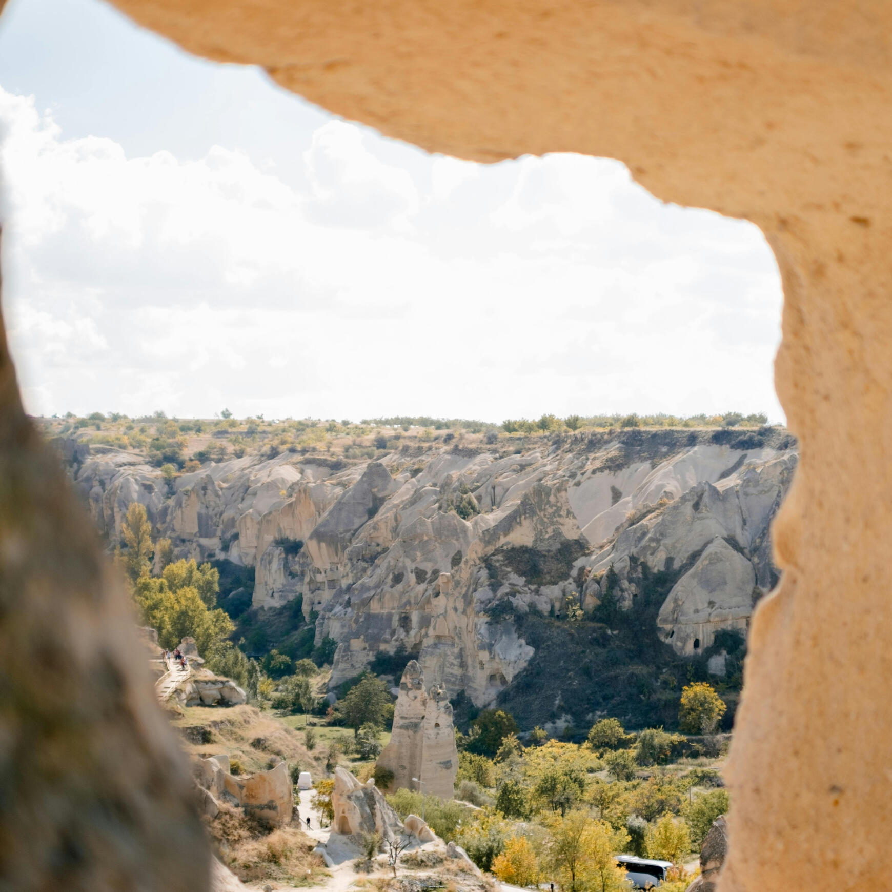 natural stone archway with a view of green and gold plant life with large rock formations in the vista