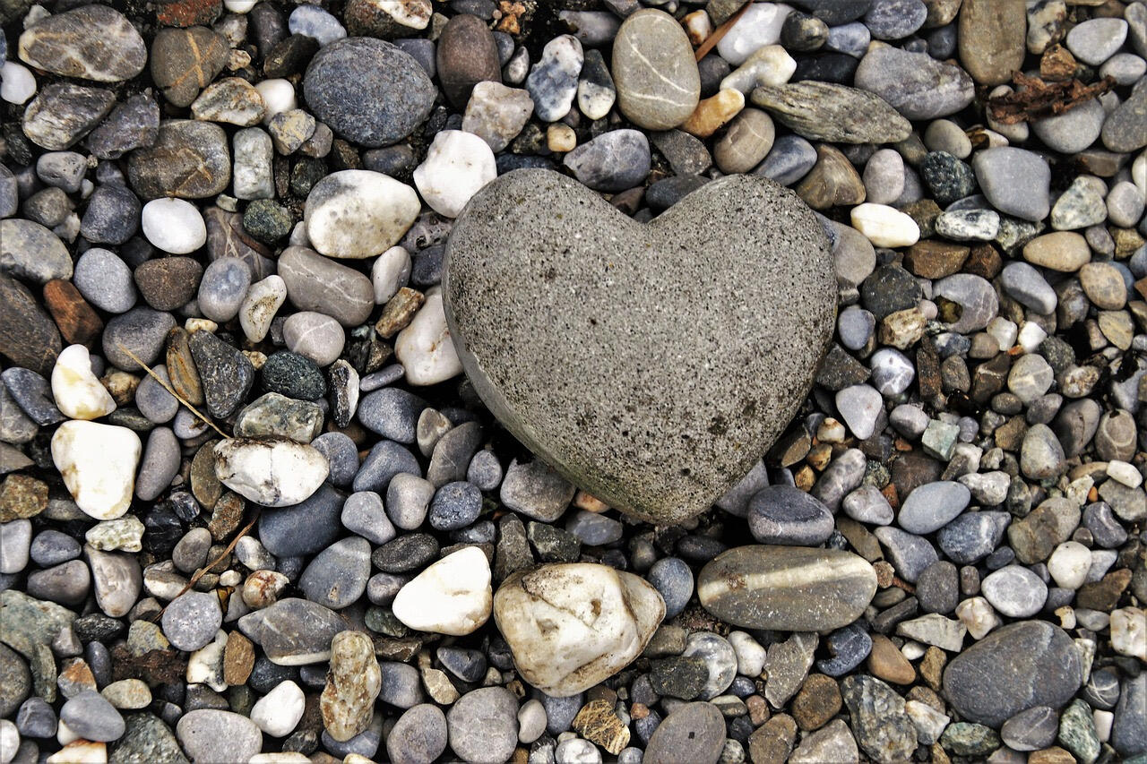 rocks on the beach with a natural heart shaped stone in the center